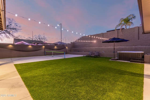 yard at dusk with central AC unit, fence, and a hot tub