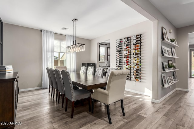 dining room with a chandelier, light wood-style flooring, visible vents, and baseboards