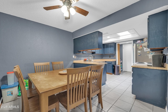 dining space featuring sink, a textured ceiling, ceiling fan, and light tile patterned flooring