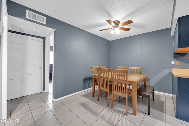 dining area with ceiling fan, a textured ceiling, and light tile patterned floors