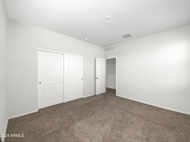 unfurnished bedroom featuring dark colored carpet and a closet