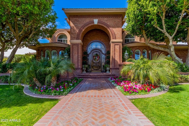 doorway to property featuring brick siding and a lawn