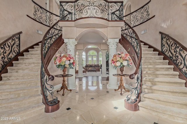 entryway featuring arched walkways, visible vents, decorative columns, and a towering ceiling