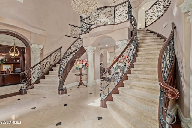 foyer with decorative columns, arched walkways, baseboards, stairway, and a high ceiling