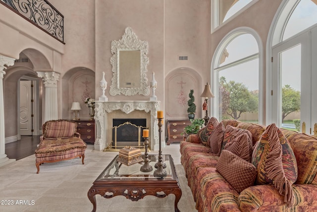 carpeted living area featuring plenty of natural light, visible vents, decorative columns, and a premium fireplace