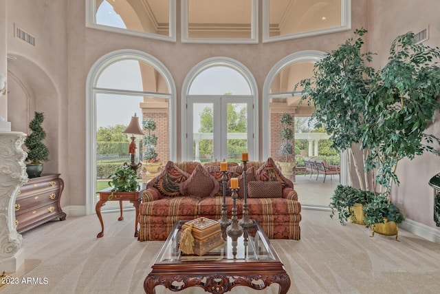 living area with carpet floors, plenty of natural light, a high ceiling, and visible vents