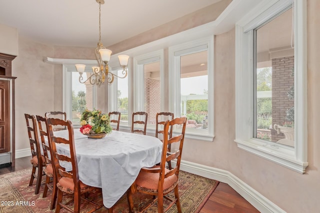 dining area featuring a notable chandelier, dark wood-type flooring, and baseboards