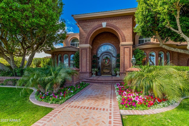 view of exterior entry featuring a yard and brick siding