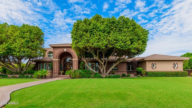 view of front of home featuring a tiled roof, a front lawn, and stucco siding