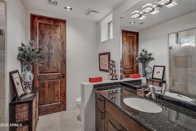 bathroom featuring vanity, toilet, a tile shower, and a wealth of natural light