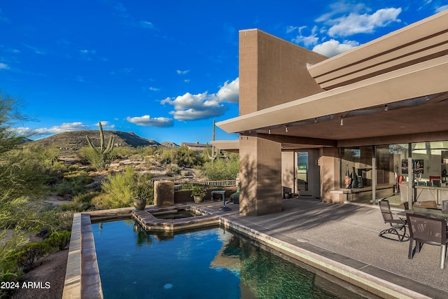 view of swimming pool featuring an in ground hot tub, a mountain view, and a patio area