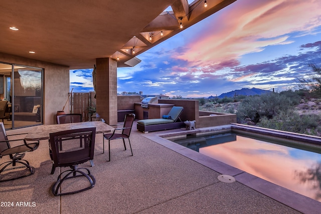 patio terrace at dusk featuring a mountain view and a pool