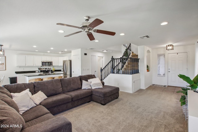 carpeted living room featuring ceiling fan and sink