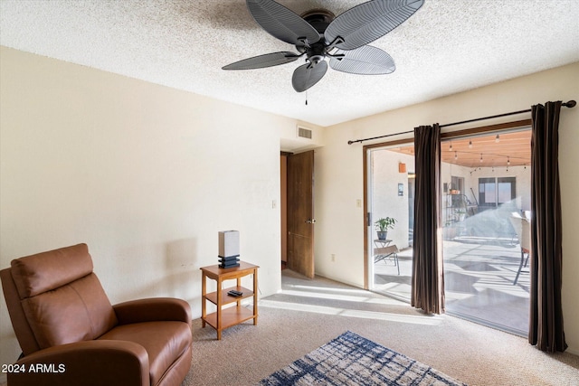 sitting room with ceiling fan, light carpet, and a textured ceiling