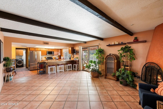 interior space with a fireplace, beam ceiling, a textured ceiling, and washer / dryer