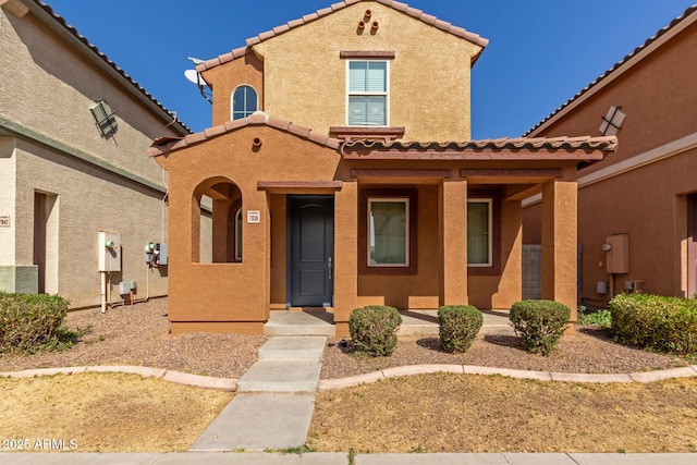 mediterranean / spanish home featuring a tile roof and stucco siding