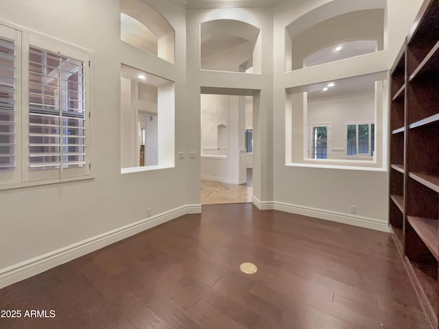 unfurnished room with a towering ceiling and dark hardwood / wood-style flooring