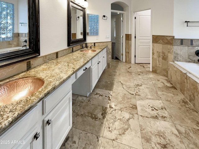 bathroom featuring vanity and tiled bath