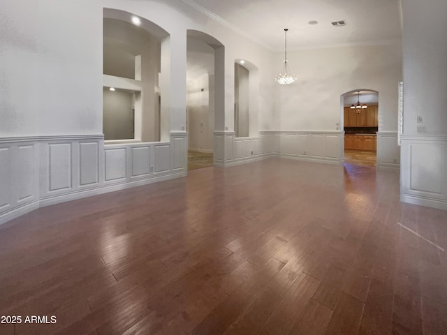 empty room with ornamental molding, dark hardwood / wood-style floors, and a chandelier