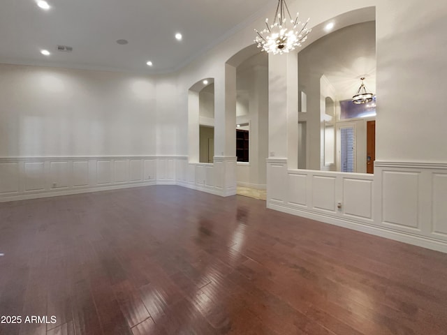 spare room featuring crown molding, dark hardwood / wood-style flooring, and a chandelier