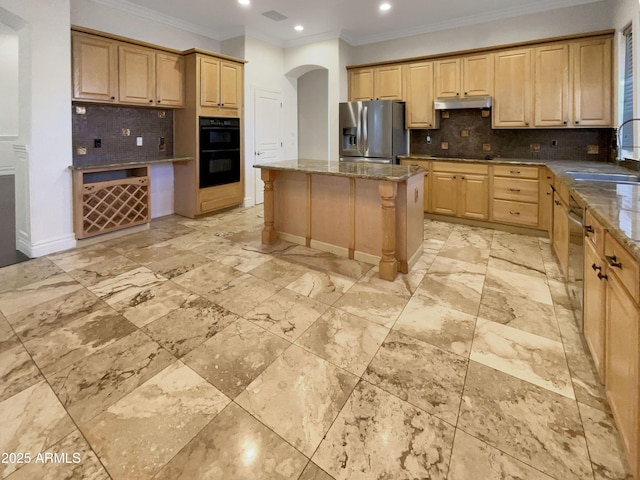 kitchen featuring dark stone countertops, backsplash, stainless steel appliances, a center island, and light brown cabinetry