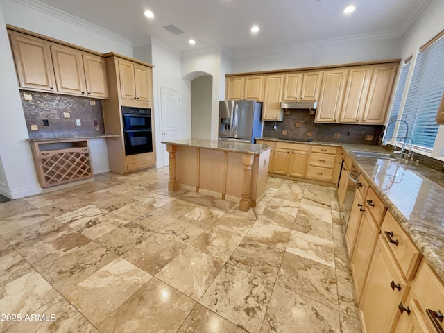 kitchen with a center island, light stone counters, tasteful backsplash, black appliances, and light brown cabinetry