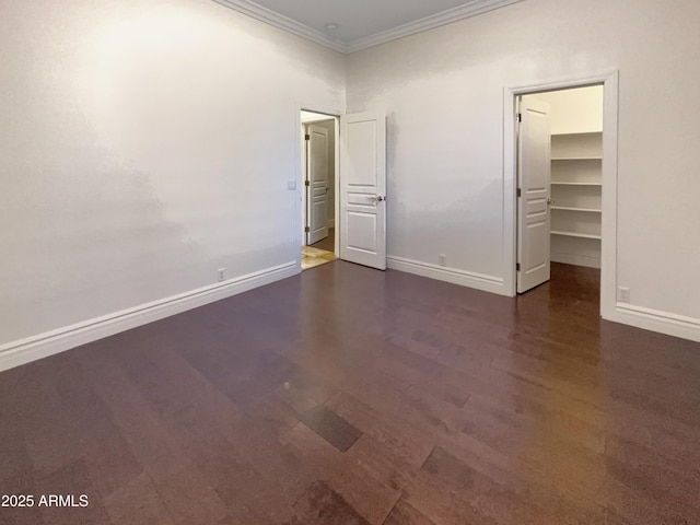 unfurnished bedroom featuring crown molding, a spacious closet, dark hardwood / wood-style flooring, and a closet