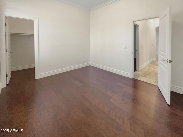 unfurnished bedroom featuring ornamental molding, a walk in closet, and a closet