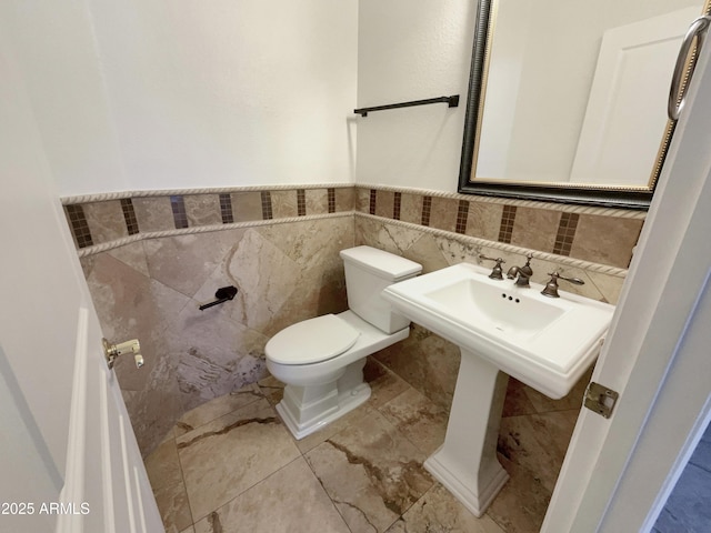 bathroom featuring tile walls and toilet