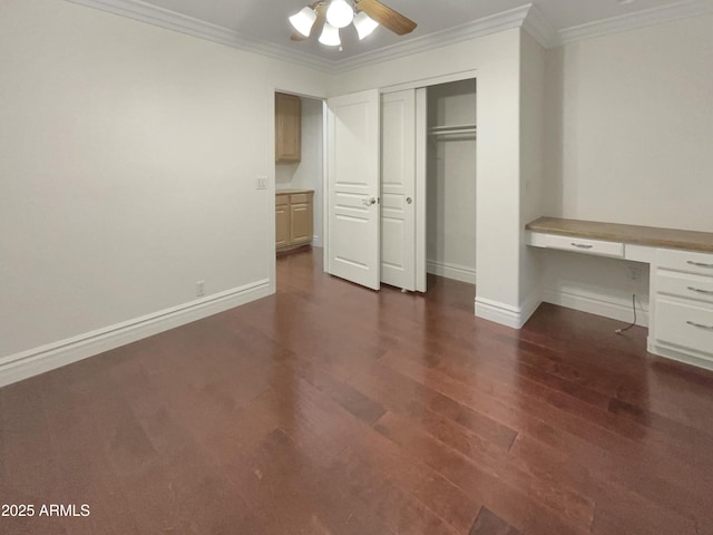 unfurnished bedroom with built in desk, ornamental molding, dark hardwood / wood-style floors, a closet, and ceiling fan