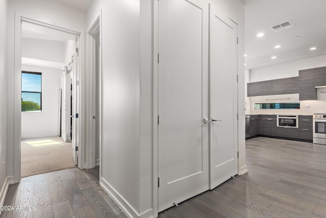 hallway featuring dark hardwood / wood-style flooring and a barn door