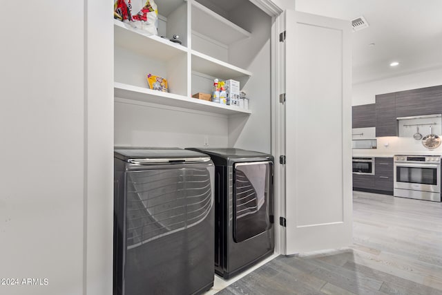 clothes washing area featuring independent washer and dryer and light hardwood / wood-style floors