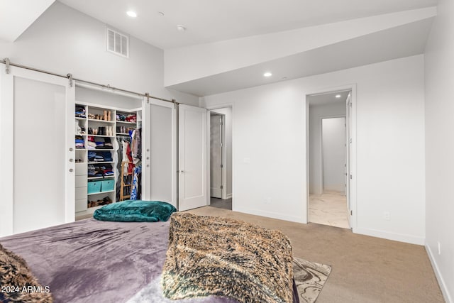 bedroom with a spacious closet, a closet, light carpet, lofted ceiling, and a barn door