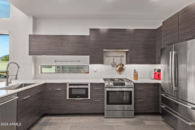 kitchen with light wood-type flooring, appliances with stainless steel finishes, sink, and dark brown cabinetry