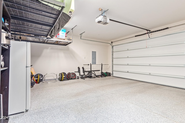 garage featuring a garage door opener, white fridge, and electric panel