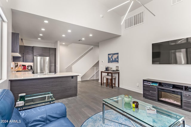 living room featuring a fireplace, a towering ceiling, and hardwood / wood-style floors