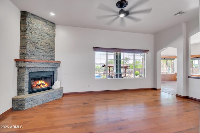 1925 W Tanya Trl, Phoenix, AZ 85086 - unfurnished living room with ceiling fan, wood finished floors, a stone fireplace, and arched walkways