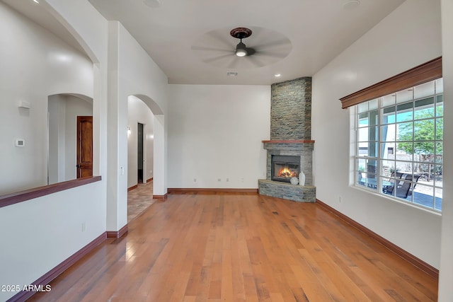 1925 W Tanya Trl, Phoenix, AZ 85086 - unfurnished living room with a ceiling fan, light wood-style floors, a stone fireplace, and arched walkways