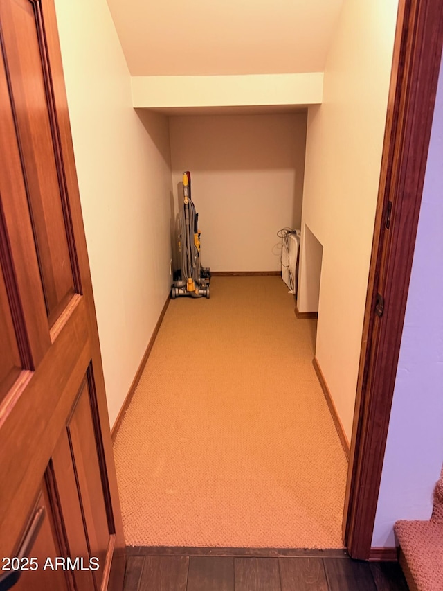 hall with baseboards and dark carpet