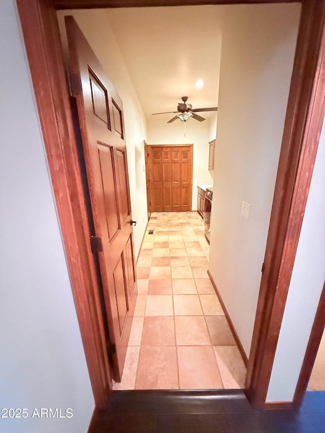 corridor with baseboards and light tile patterned floors