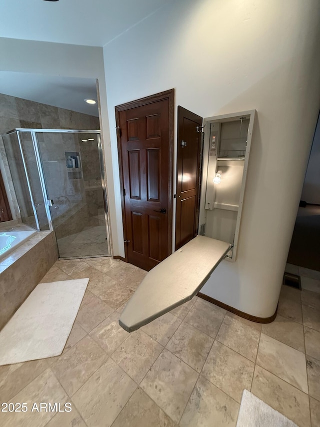 bathroom with a shower stall, baseboards, and a garden tub