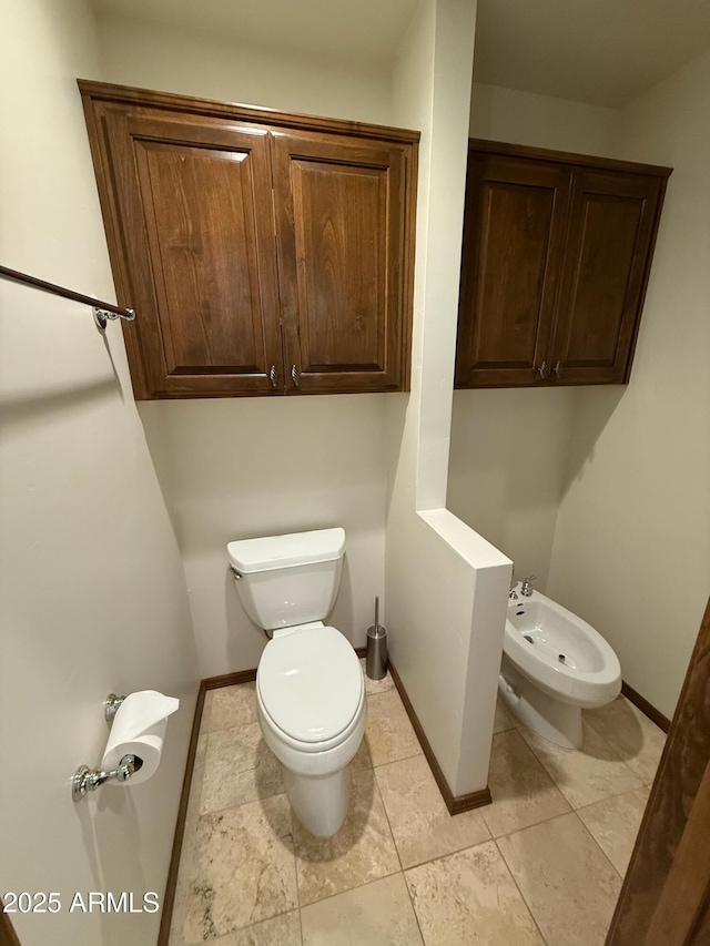 half bath with baseboards, a bidet, and toilet