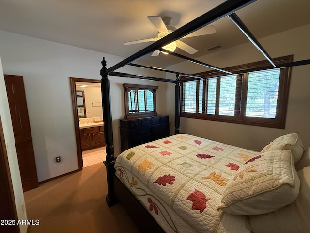 bedroom featuring light carpet, visible vents, ensuite bath, and a ceiling fan