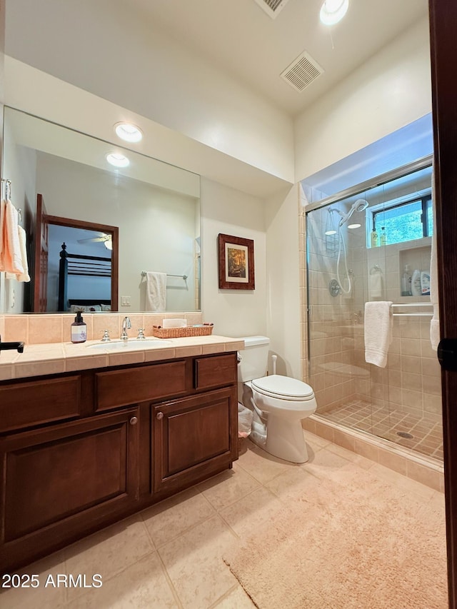 full bath featuring toilet, vanity, a shower stall, tile patterned flooring, and visible vents