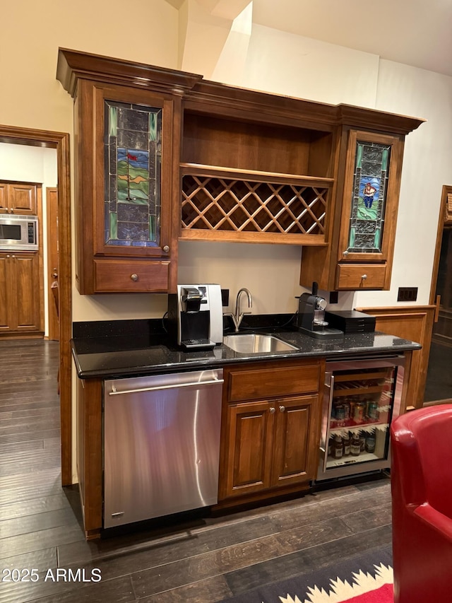 bar featuring dark wood-type flooring, indoor wet bar, a sink, and stainless steel appliances