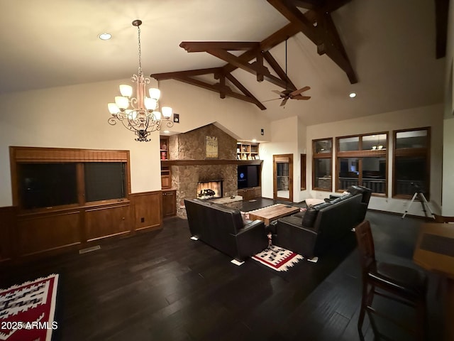 living area with ceiling fan with notable chandelier, a wainscoted wall, beamed ceiling, a fireplace, and wood finished floors