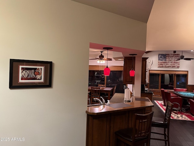 interior space featuring hanging light fixtures, a breakfast bar, and ceiling fan