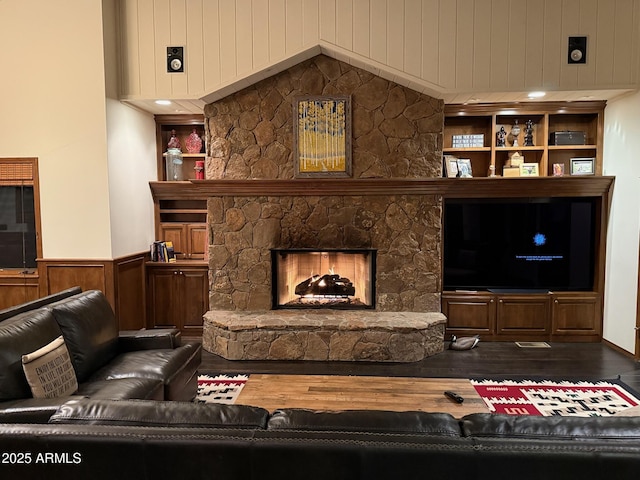 living room featuring a wainscoted wall, a stone fireplace, and wood finished floors