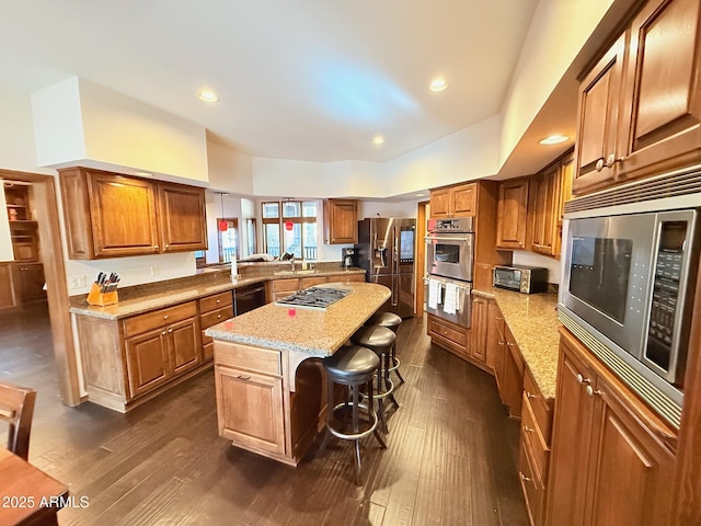 kitchen featuring a center island, brown cabinetry, a breakfast bar, and stainless steel appliances