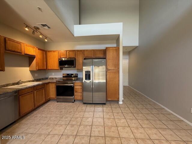 15655 N 29th St, Phoenix, AZ 85032 - kitchen with stainless steel appliances, brown cabinets, light tile patterned floors, and track lighting